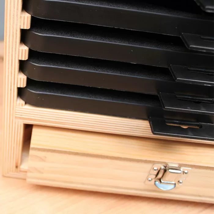 Stacked black metal woodworking jigs in a wooden storage case with latch on a workshop table.