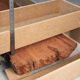 Measuring rough wood slab with a ruler inside a woodworking jig for precise cutting