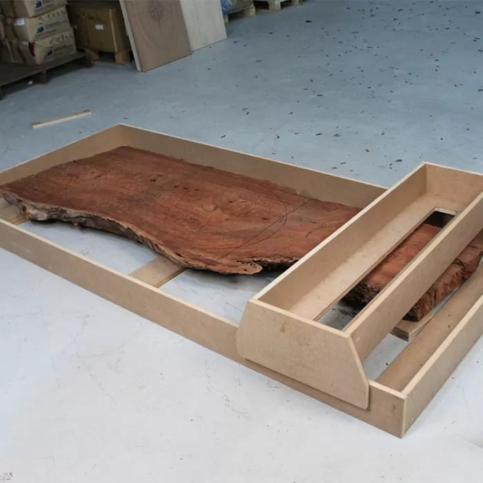 Wood slab in router sled jig on workshop floor for flattening and woodworking projects