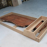 Wood slab in router sled jig on workshop floor for flattening and woodworking projects