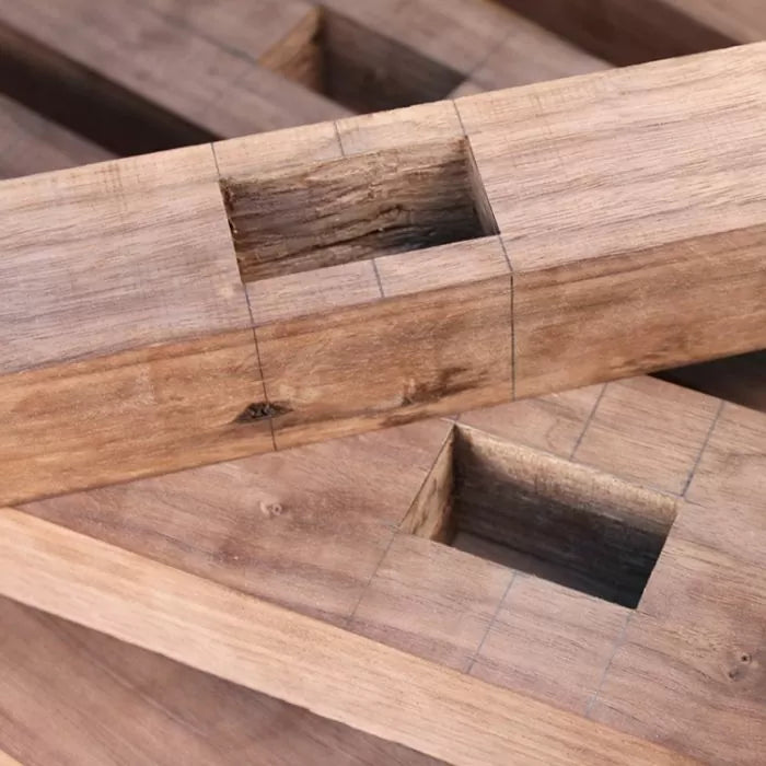 Close-up of mortise joints cut into hardwood, marked with pencil lines for precise woodworking.