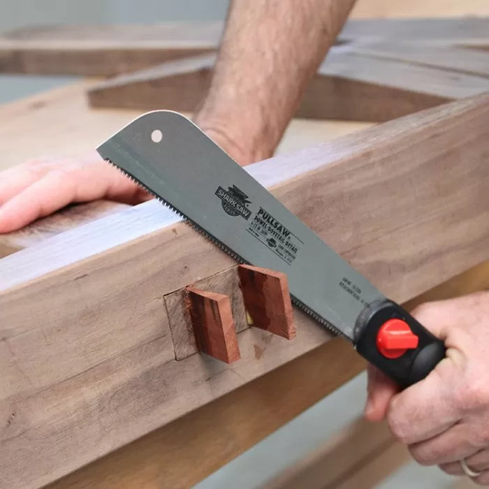 Woodworker using pull saw to cut wooden tenons on workbench