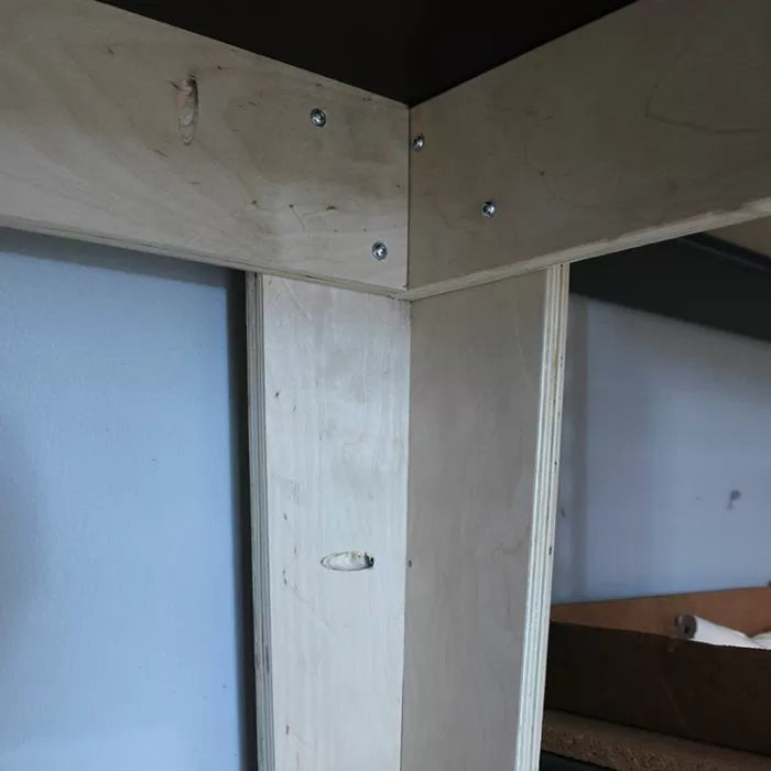 Close-up of woodworking joint on a plywood workbench frame with screws and pocket holes