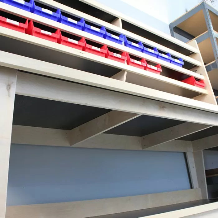 Wood shop workbench with red and blue storage bins and open shelving for tool organization