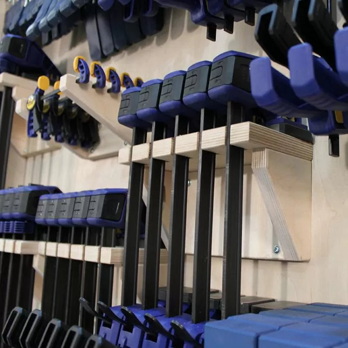 Woodworking bar clamps organized on a wall-mounted clamp rack in a workshop