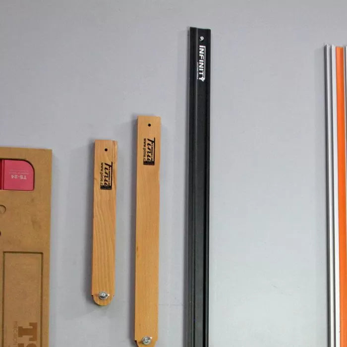 Wall-mounted black aluminum T-track and wood jig holders for woodworking organization