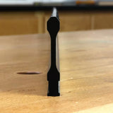 Profile view of black woodworking router bit rail on wooden workbench, precise cut edge