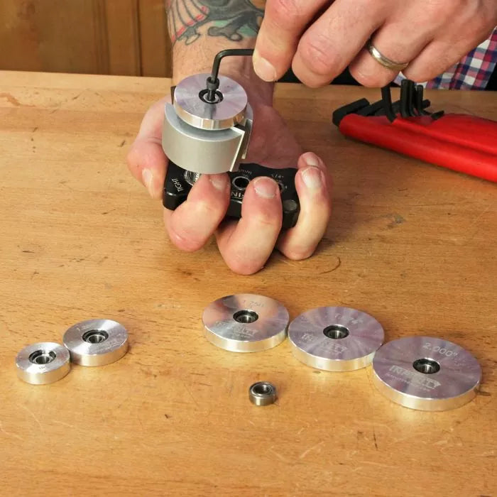 Person assembling woodworking router bearing guides with hex key on workbench