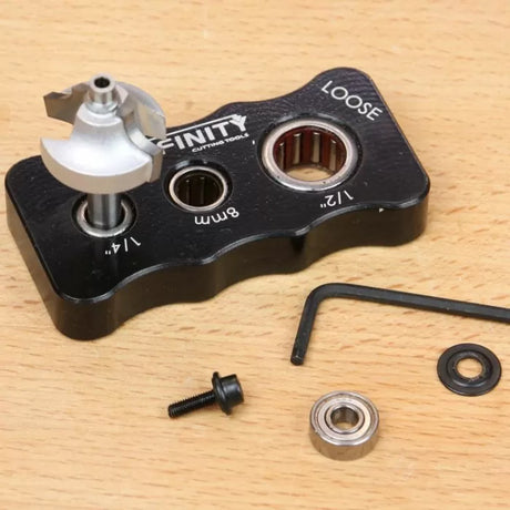 Router bit setup block with bearings, screw, washer, and hex key on a wood surface