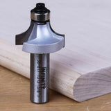 Roundover router bit for woodworking shown next to rounded wood edge