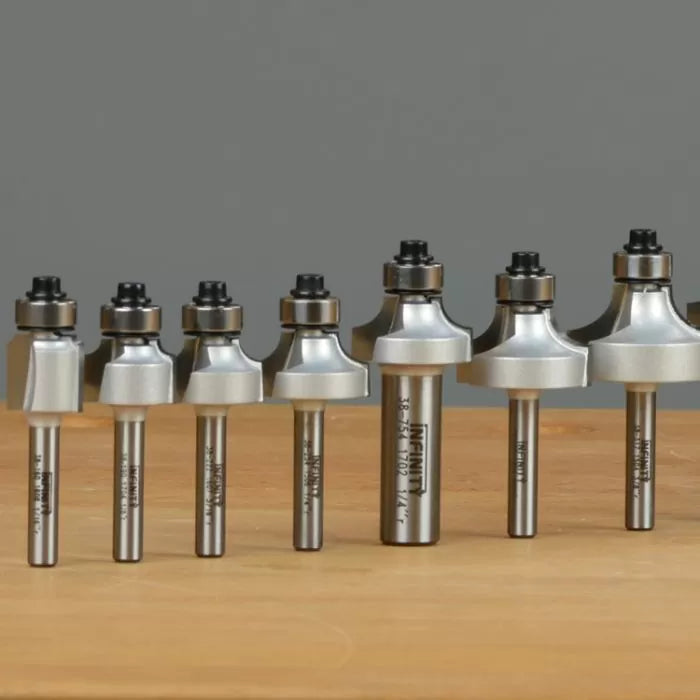 Set of varying roundover router bits on a wooden surface for woodworking.