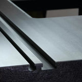 Close-up of a cast iron router table top with precision dual miter slots for woodworking