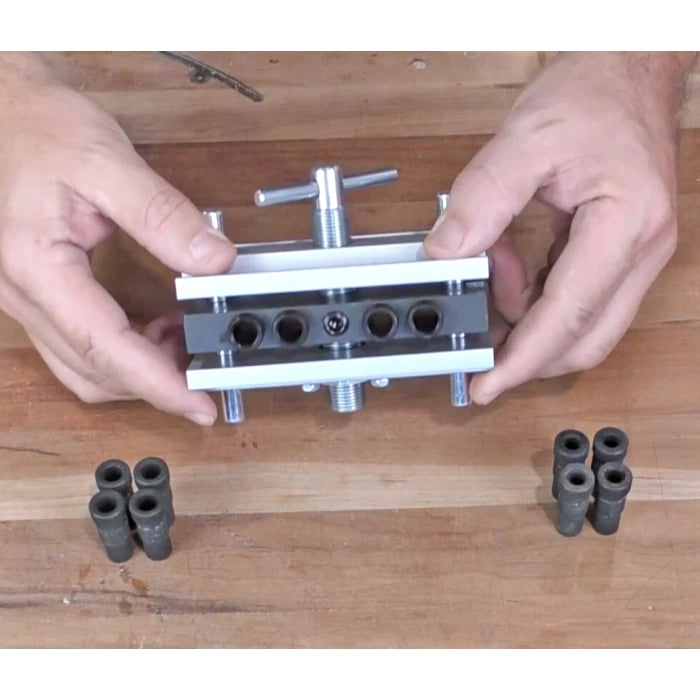 Woodworking dowel jig with bushings on a workbench, hands holding alignment tool