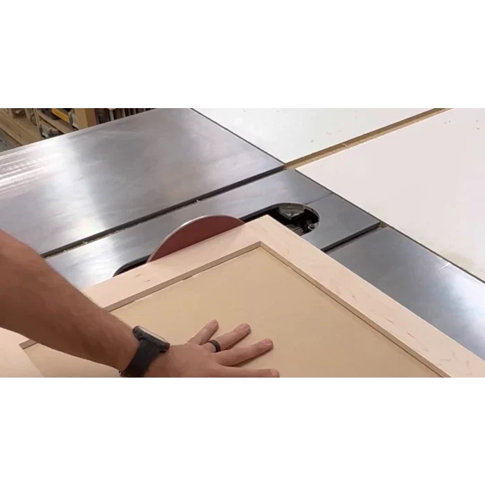 Woodworker using table saw to cut MDF panel in workshop, precision woodworking tools visible