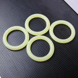 Four yellow router bit O-rings on textured black surface, woodworking tool accessory