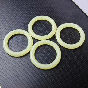 Four yellow router bit O-rings on textured black surface, woodworking tool accessory