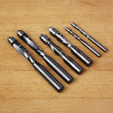 Set of spiral flush trim router bits on a wooden surface, various sizes for woodworking.