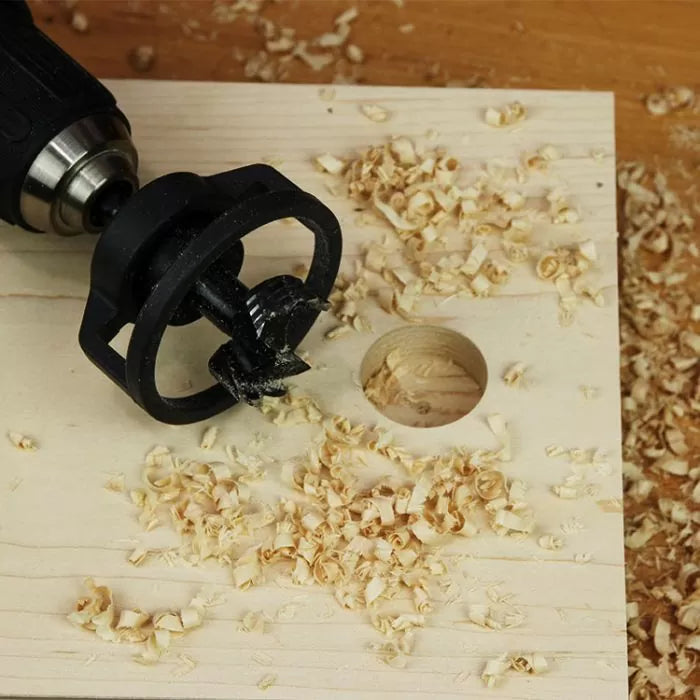 Drill stop accessory on power drill creating clean hole in wooden board with wood shavings