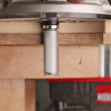 Straight router bit cutting wood edge on a router table, woodworking tool in use