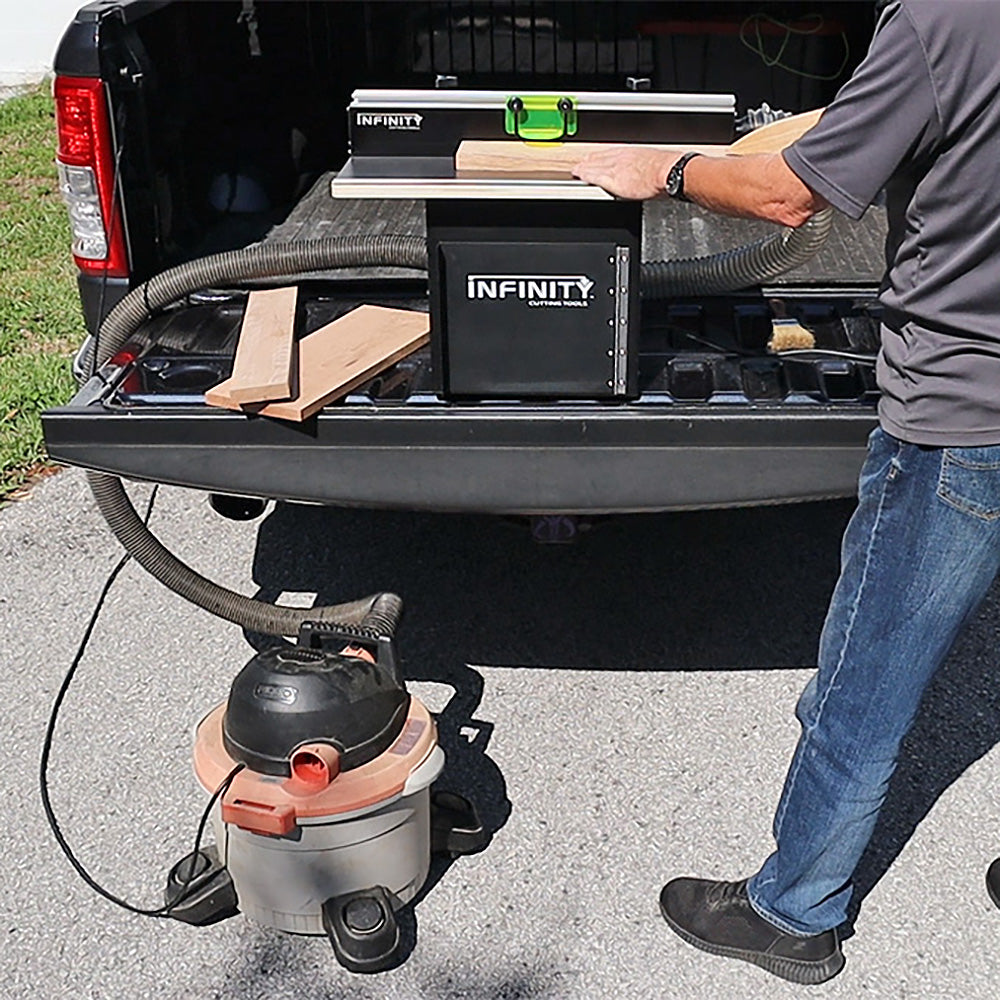 Man using a portable router table and dust collector for woodworking on a truck bed