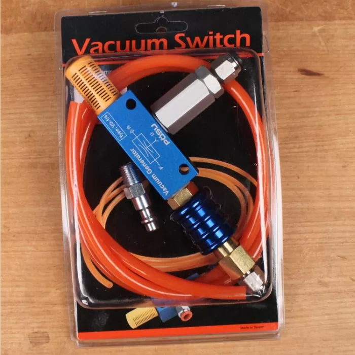 Vacuum switch kit with orange tubing, blue and silver metal connectors, in retail packaging on wood surface