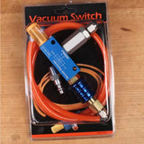 Vacuum switch kit with orange tubing, blue and silver metal connectors, in retail packaging on wood surface