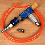 Vacuum generator tool with orange hose and metal fittings on a wood surface