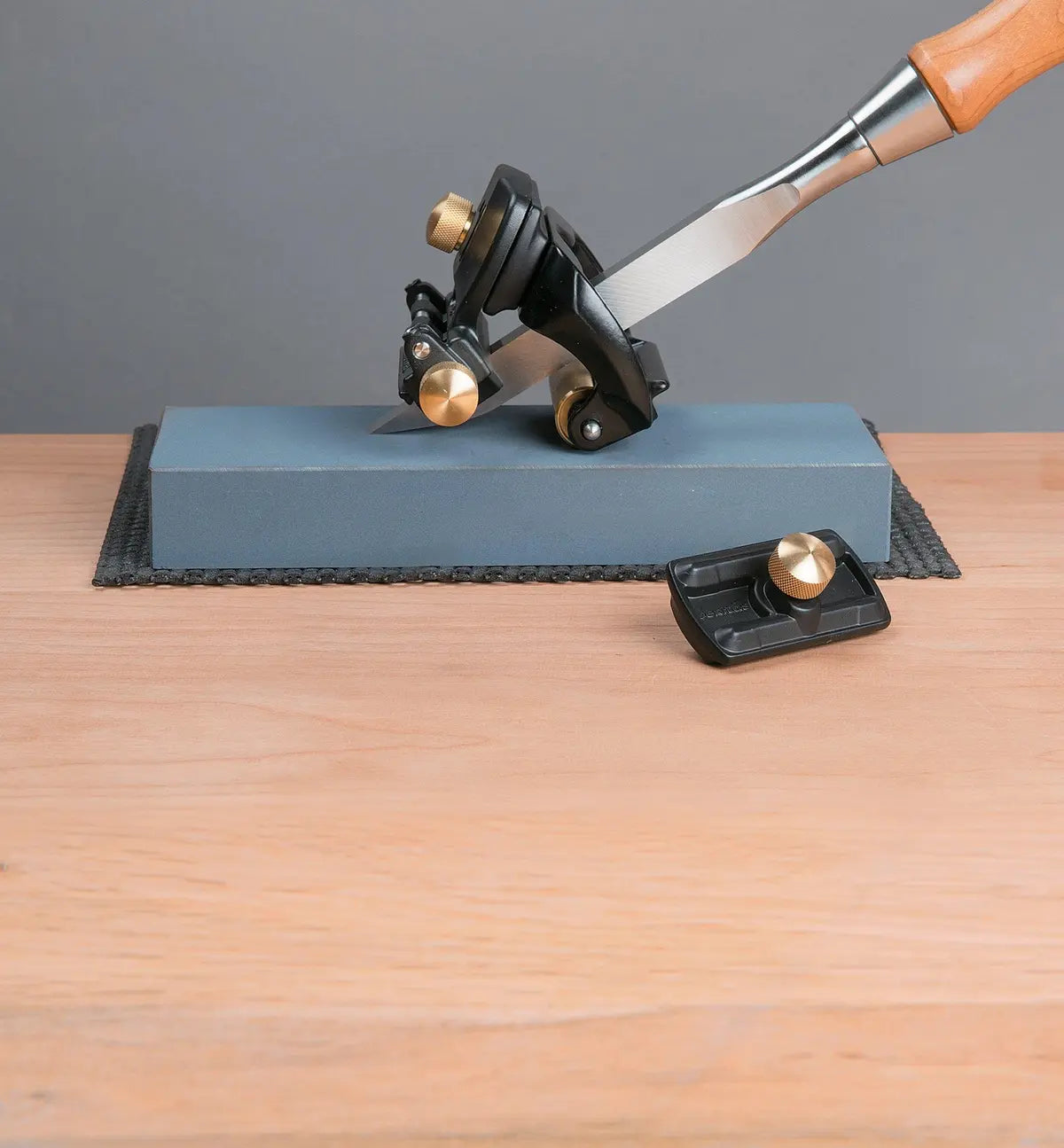 Chisel sharpening guide on honing stone with brass adjustment knobs for precise woodworking.