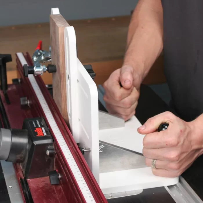 Woodworker using router table fence system for precise edge routing on wood
