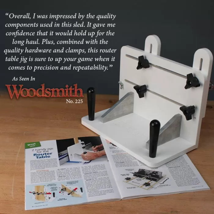 Router table sled jig with adjustable clamps and handles on a workbench, woodworking magazine underneath.