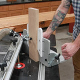 Woodworker adjusting router table fence with dust collection hose and vertical board