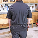 Rear view of person wearing a black waist tool apron in a woodworking shop.
